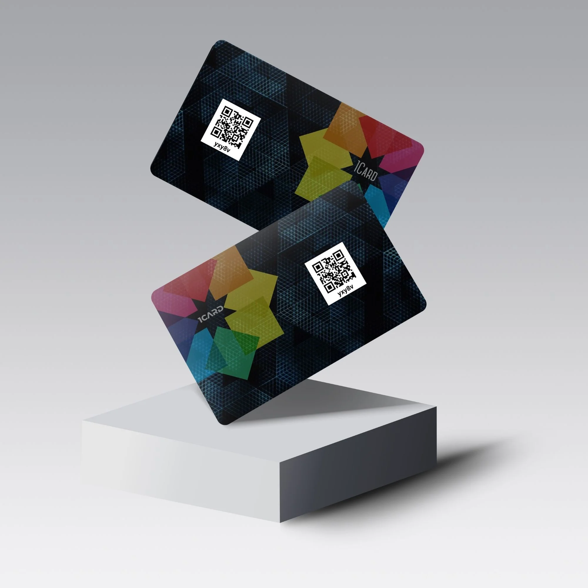 Two 1Card Duo cards with colorful geometric patterns and QR codes on a gray pedestal.