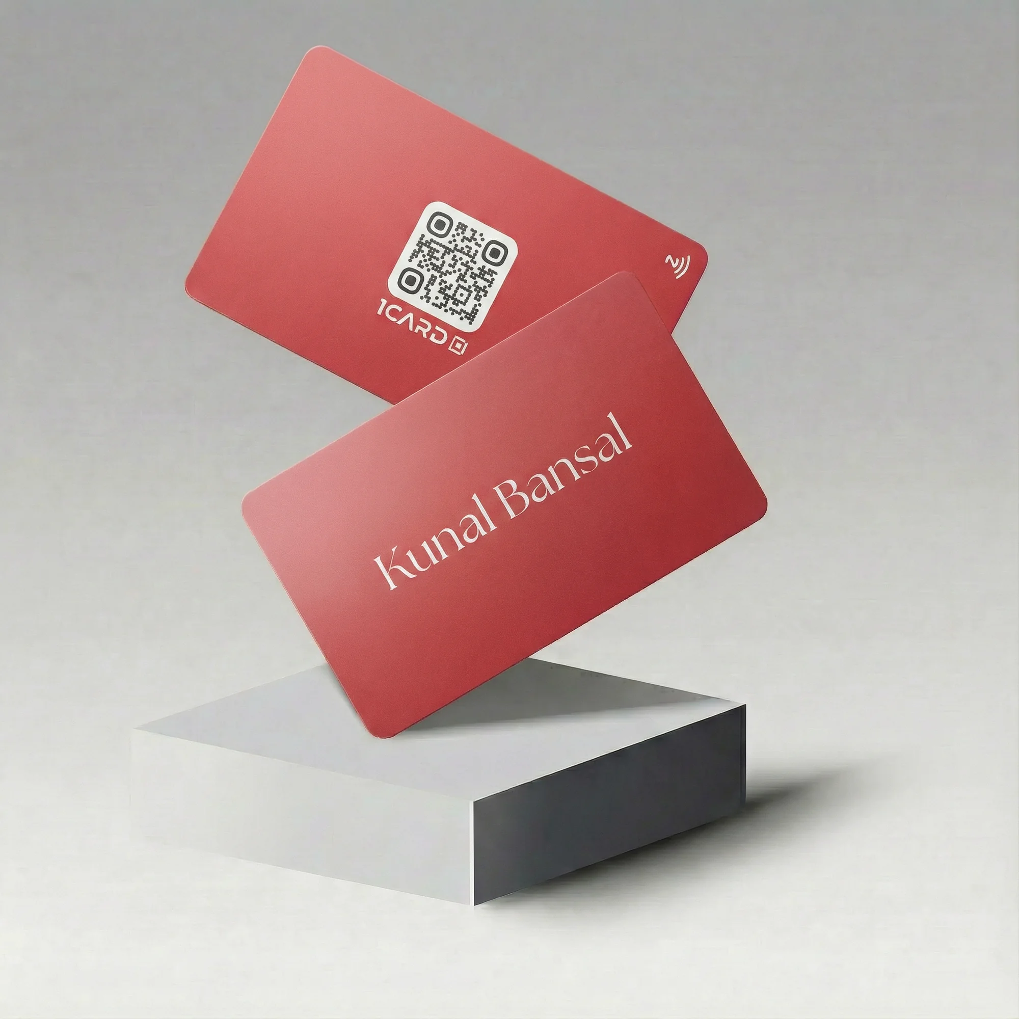 Two coral-colored NFC cards with "Kunal Bansal" and a QR code, displayed on a white block.