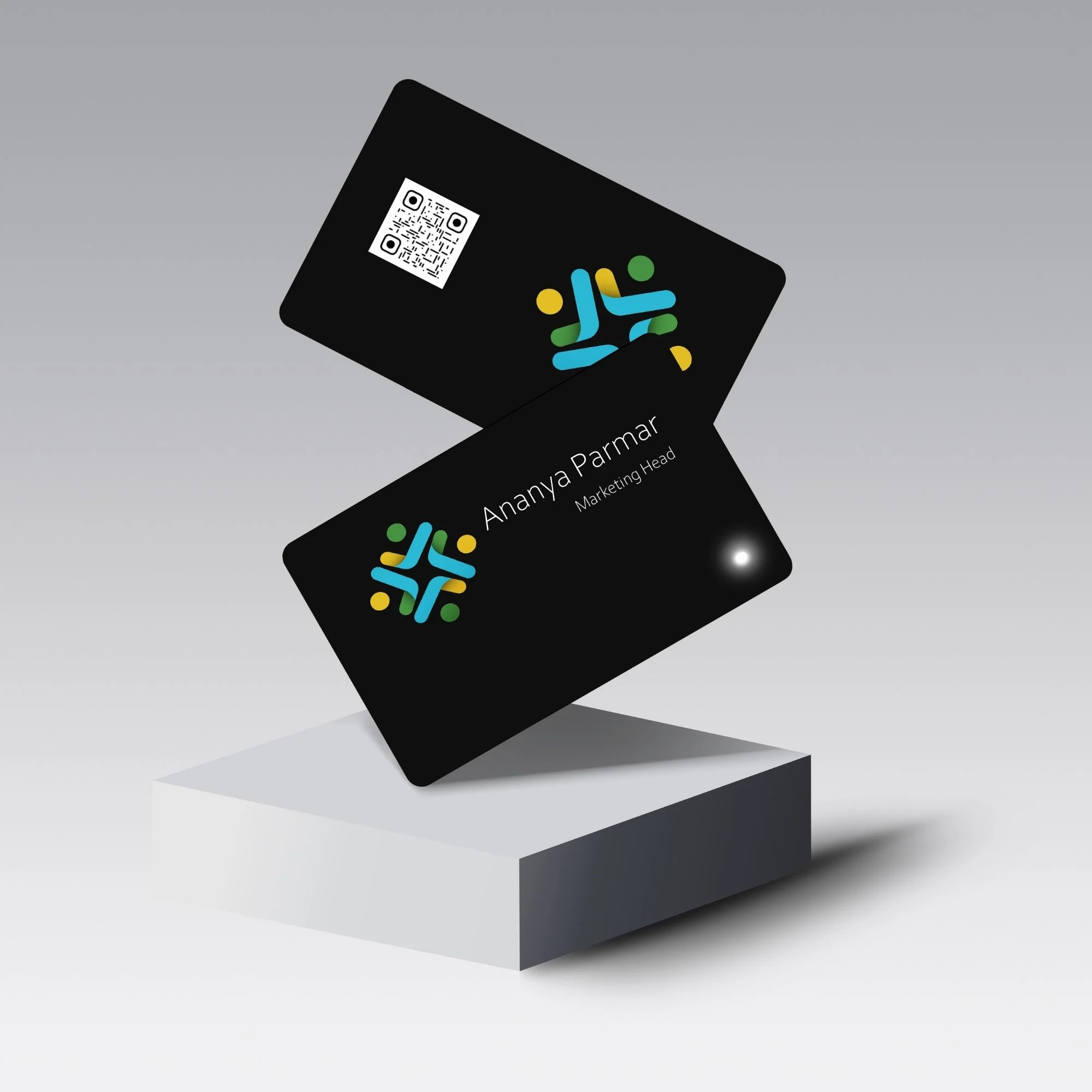 Two black NFC cards with colorful logos and QR codes, one displaying "Ananya Parmar, Marketing Head," on a gray pedestal.