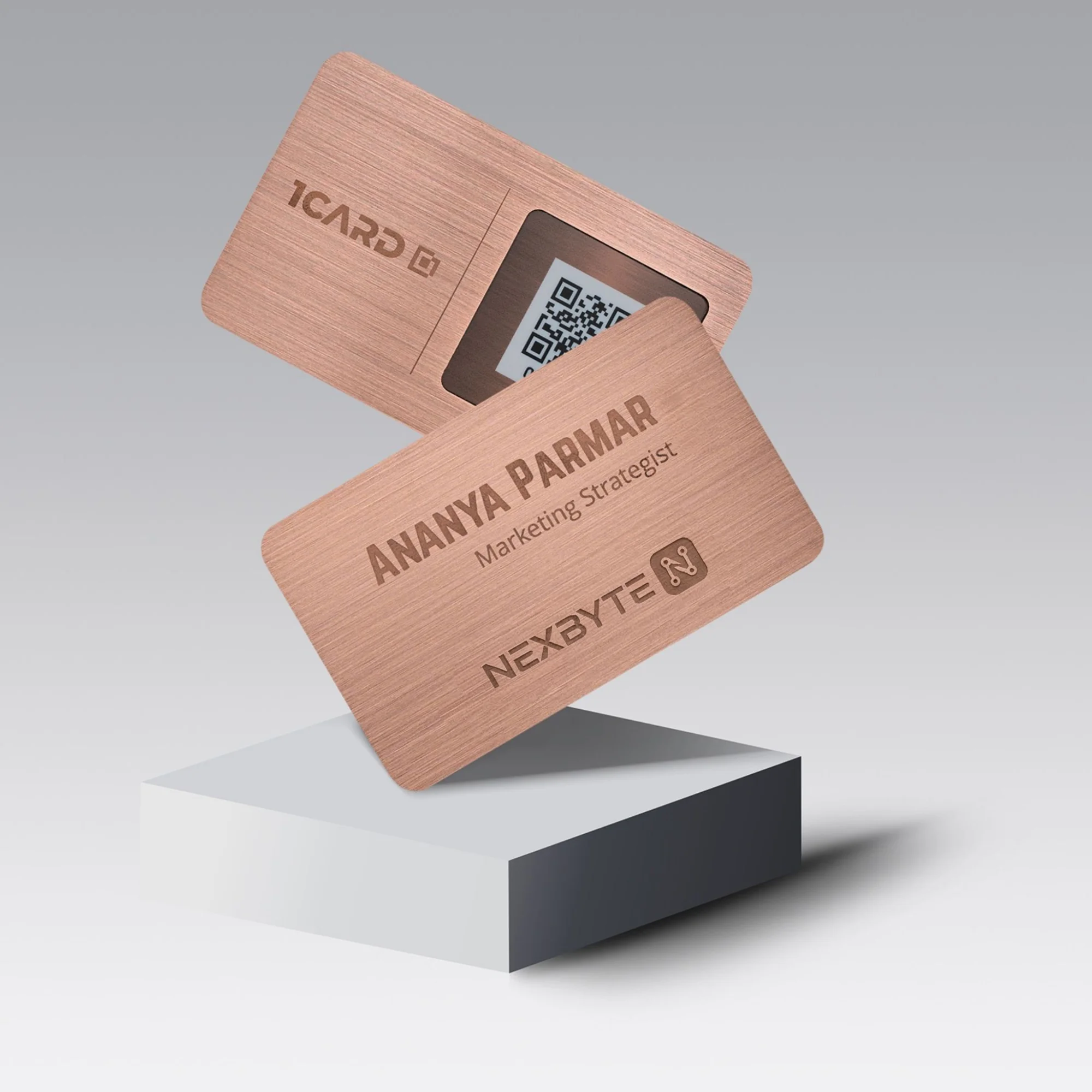 Two copper-colored cards with engraved text, one showing a QR code, on a white platform.