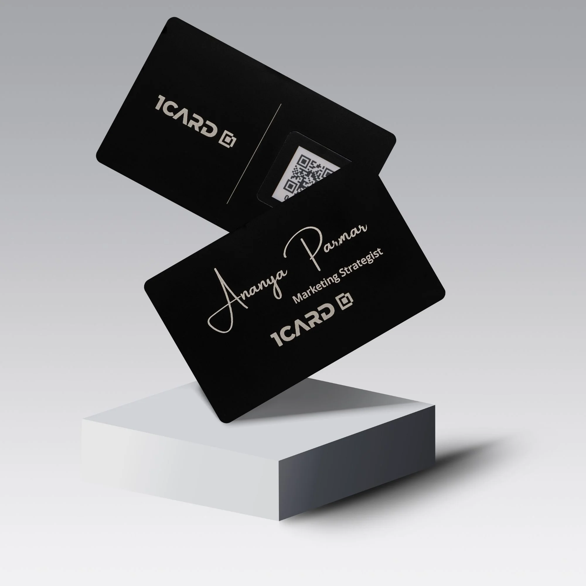 Two black metal cards with "1CARD" logo and QR code, one displaying "Ananya Parmar, Marketing Strategist.