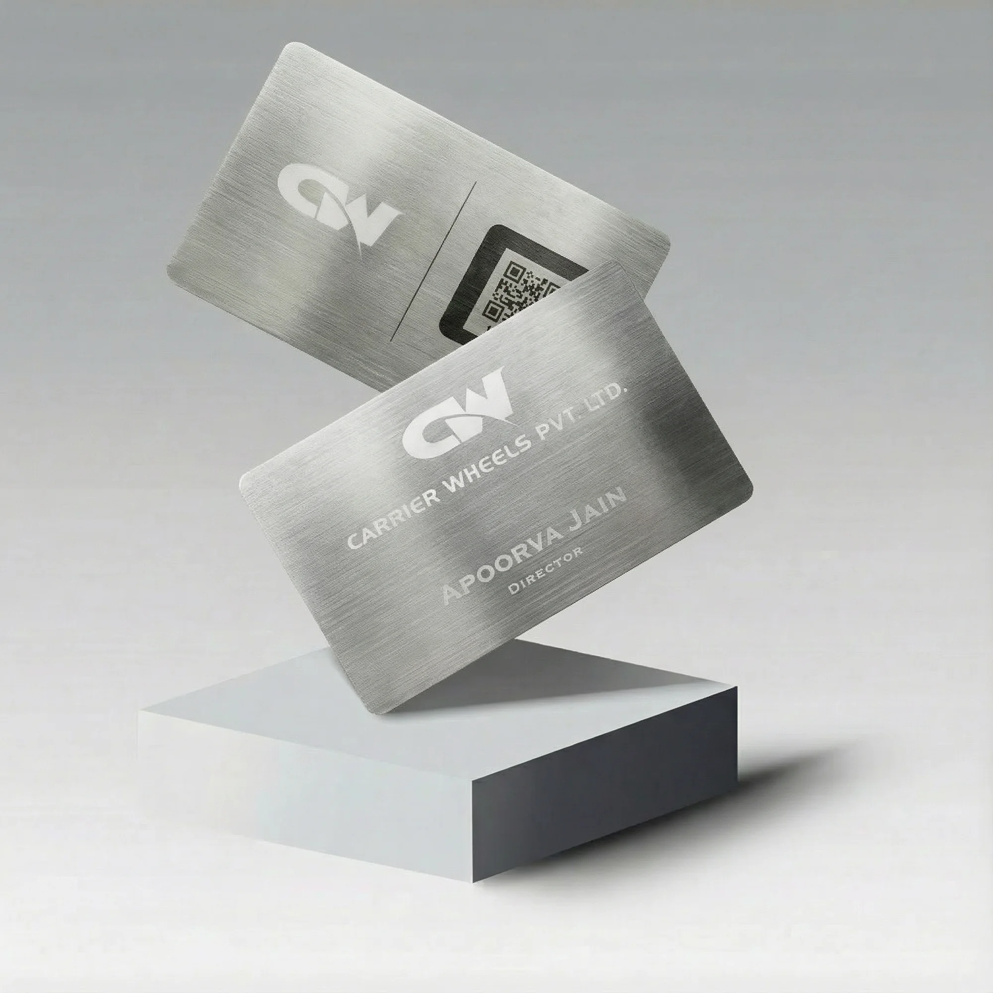 Two stainless steel business cards with engraved text and a QR code, displayed on a white block.