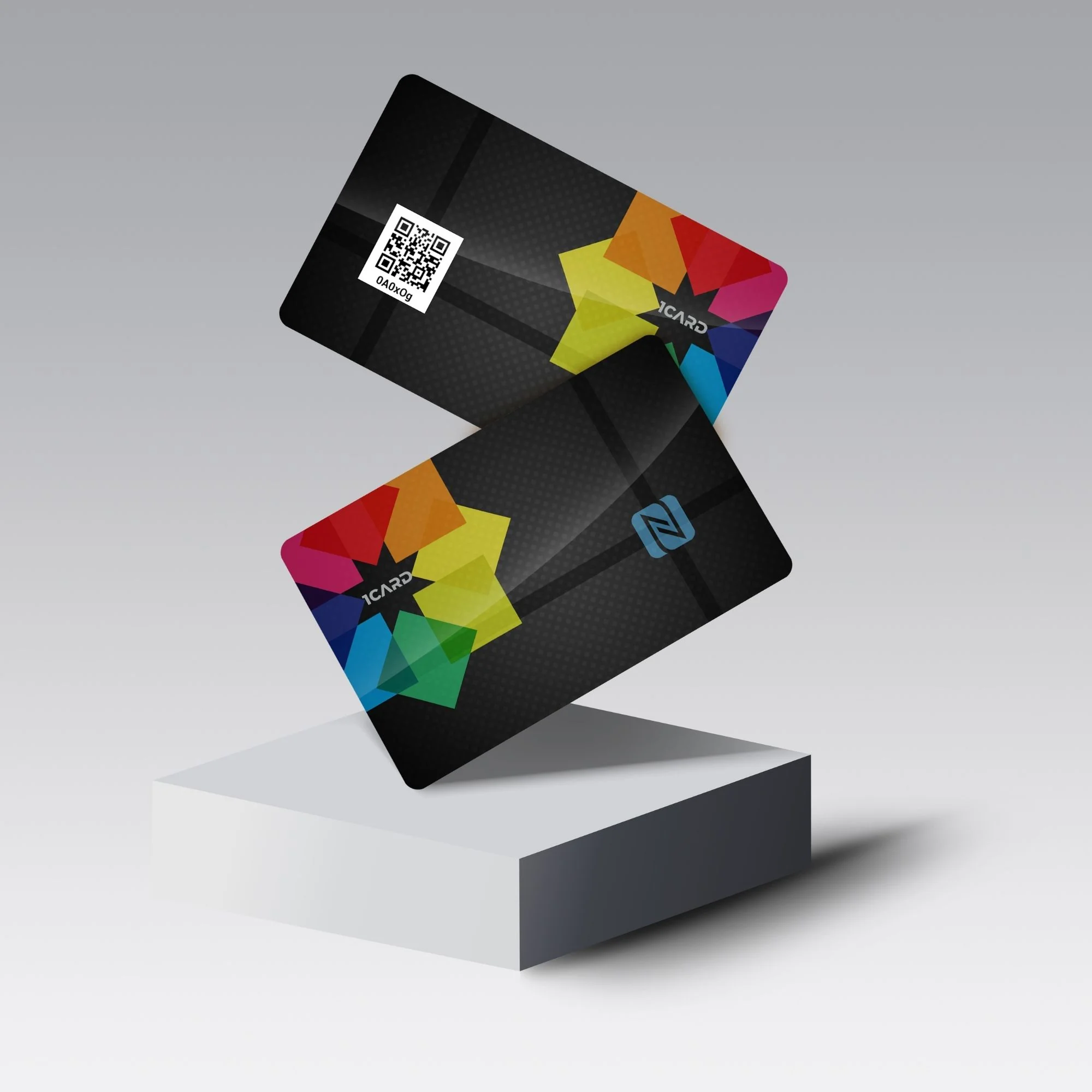 Two black cards with colorful geometric designs and a QR code, displayed on a white pedestal against a gray background.
